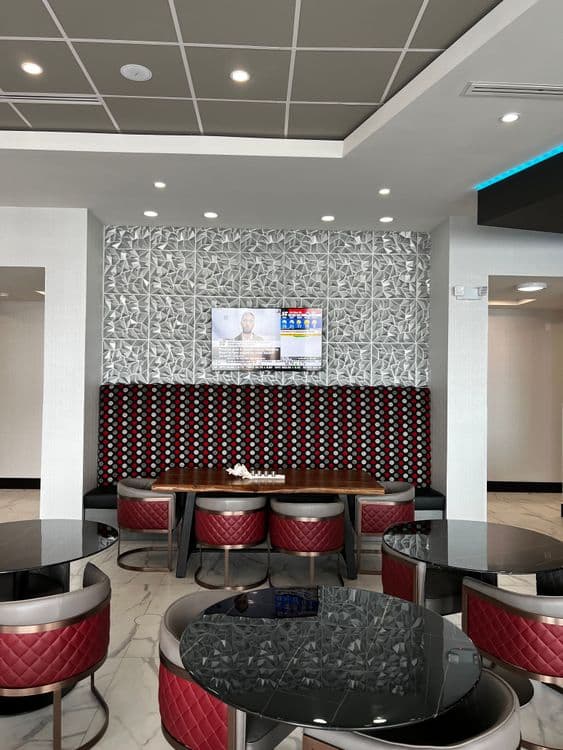 Elegant dining area with long red upholstered benches, dark tables, and a textured silver wall.