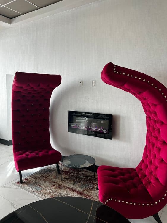 Two luxurious red velvet chairs with studded detailing in a brightly lit room.